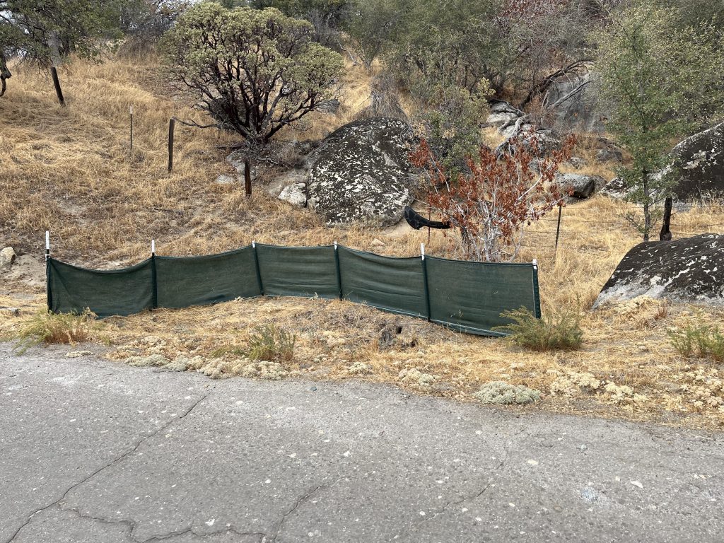 Green weather barrier by a hill and pavement